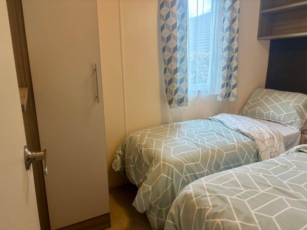 A bedroom with two beds and a wardrobe at Caravan in Holcot Sleeps 6 Max 6 people Max 4 adults per booking Pet Friendly Holcot near Moulton