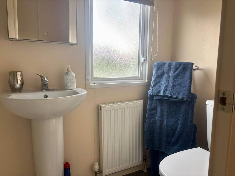A bathroom with a sink, mirror, toilet, and towels at Caravan in Holcot Sleeps 6 Max 6 people Max 4 adults per booking Pet Friendly Holcot near Moulton