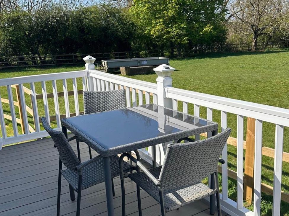 A table and chairs on a deck area at Caravan in Holcot Sleeps 6 Max 6 people Max 4 adults per booking Pet Friendly in Holcot near Moulton