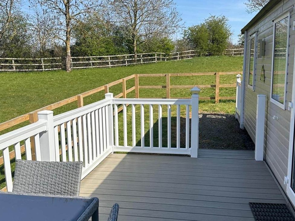 A deck with a mobile home and a fence at Caravan in Holcot Sleeps 6 Max 6 people Max 4 adults per booking Pet Friendly Holcot near Moulton