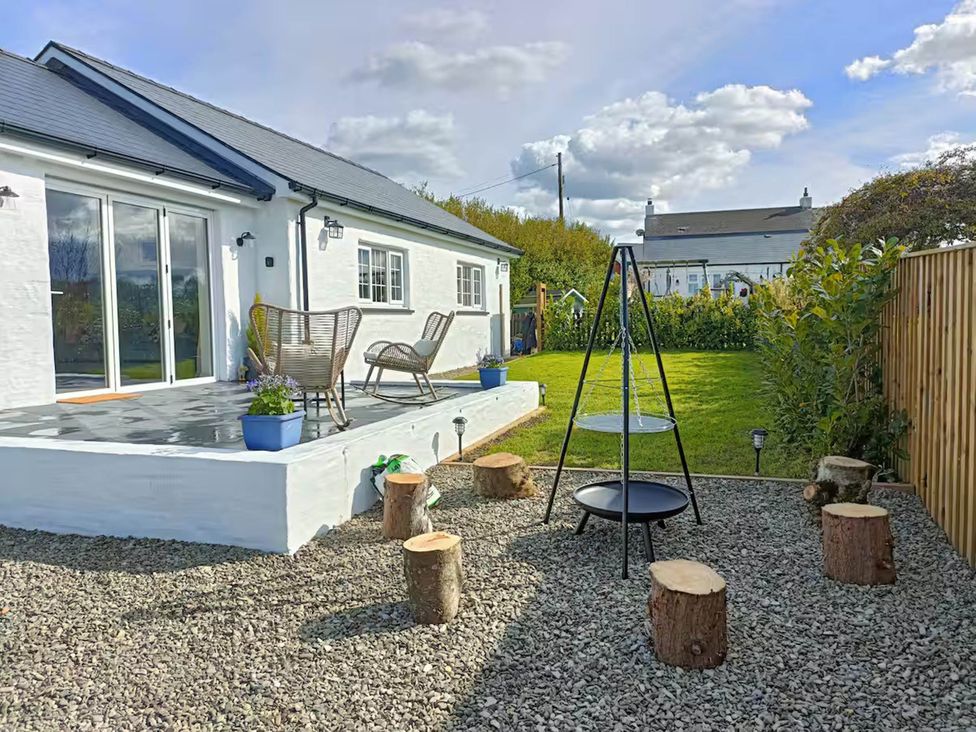 A garden with a deck, chairs, and a swing at Aberporth 2 Bed Cottage Sleeps 4 Pet Friendly Parcllyn near Aberporth