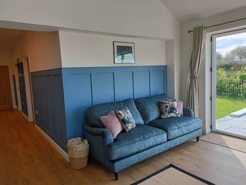 A living room with a blue sofa and a door leading to the garden at Aberporth 2 Bed Cottage Sleeps 4 Pet Friendly Parcllyn near Aberporth