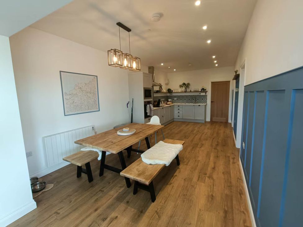 A dining room with a wooden table and benches at Aberporth 2 Bed Cottage Sleeps 4 Pet Friendly Parcllyn near Aberporth
