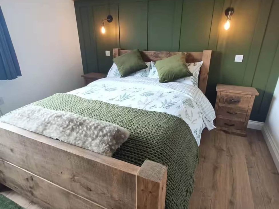 A bedroom with a wooden bed and bedside table at Aberporth 2 Bed Cottage Sleeps 4 Pet Friendly in Parcllyn near Aberporth