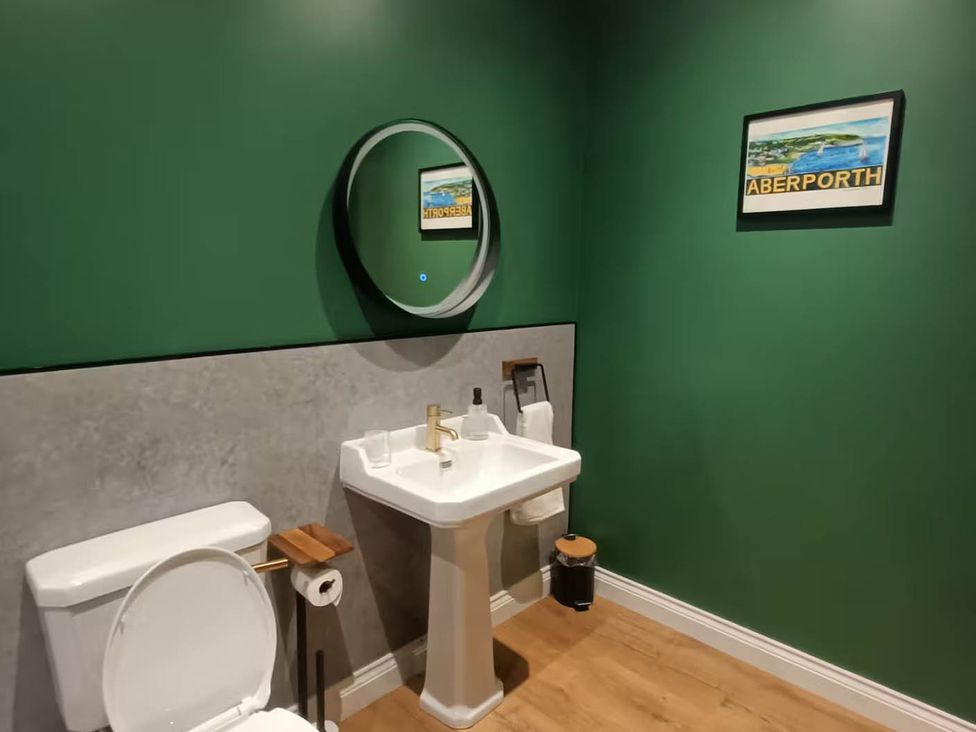A bathroom featuring a sink, toilet, and mirror at Aberporth 2 Bed Cottage Sleeps 4 Pet Friendly near Parcllyn