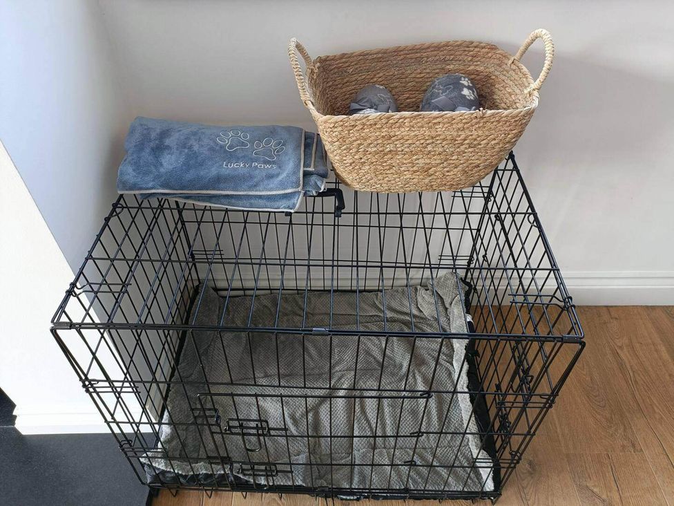 A dog crate with a blanket and a woven basket at Aberporth 2 Bed Cottage Sleeps 4 Pet Friendly in Parcllyn near Aberporth