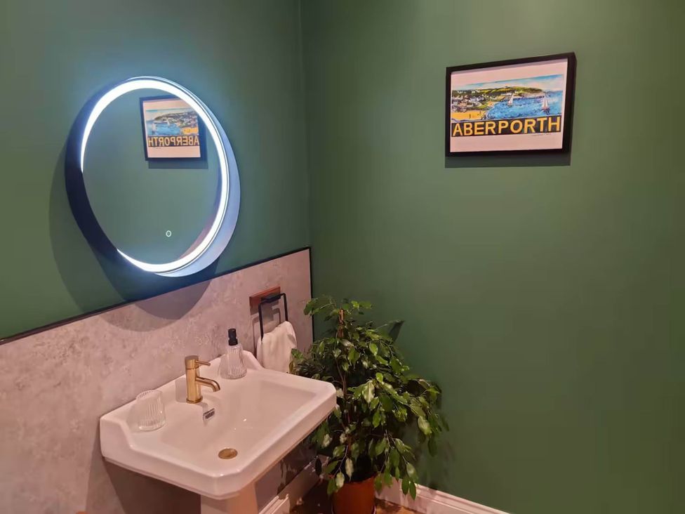 A bathroom with a sink and round mirror at Aberporth 2 Bed Cottage Sleeps 4 Pet Friendly Parcllyn near Aberporth