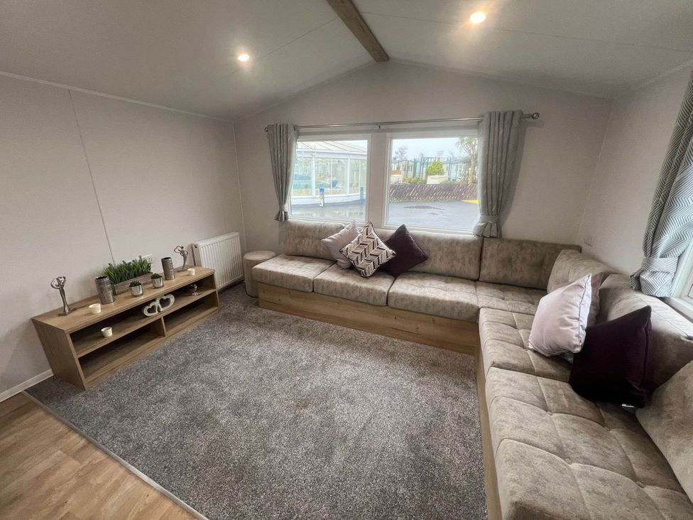 A living room with a sofa and television stand at 8 Guests Swimming Pool 1min to the Beach in Heacham