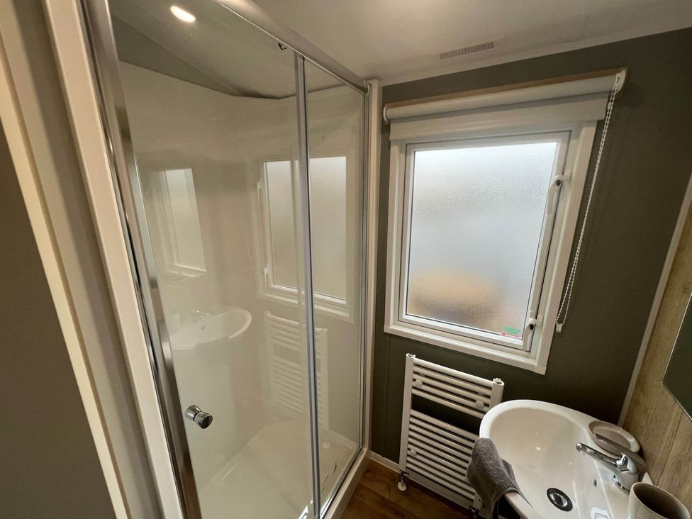 A bathroom featuring a shower, sink, and window at 8 Guests Swimming Pool 1min to the Beach Heacham