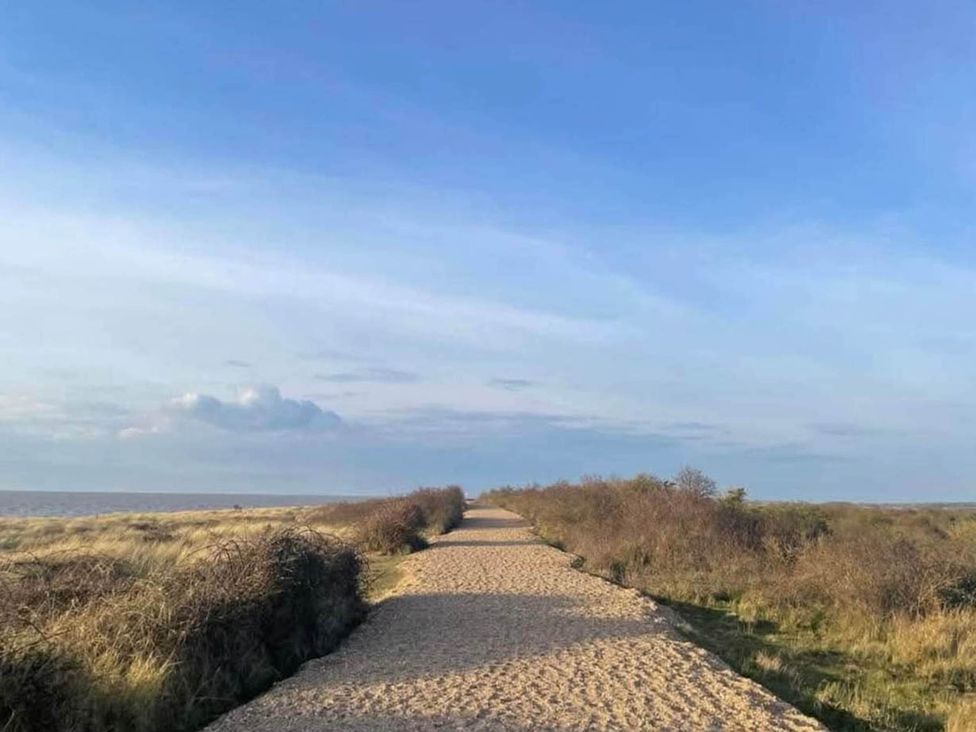 A sandy path surrounded by grass and bushes at 8 Guests Swimming Pool 1min to the Beach Heacham