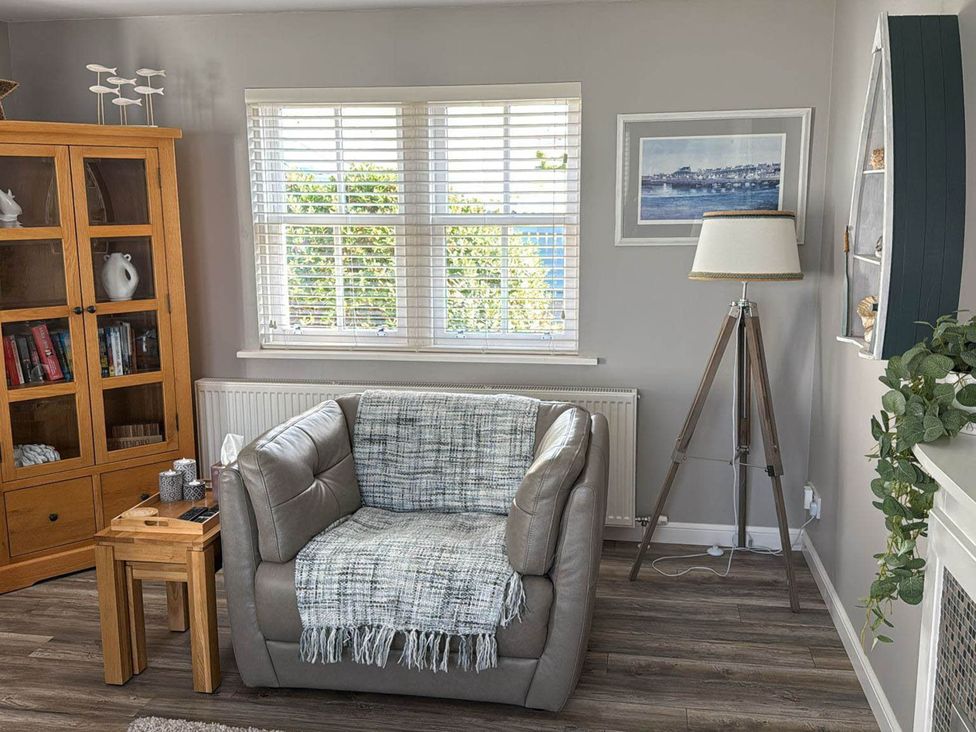 A living room with an armchair and bookshelf at Findochty Beach house Private Garden BeachFront, Findochty