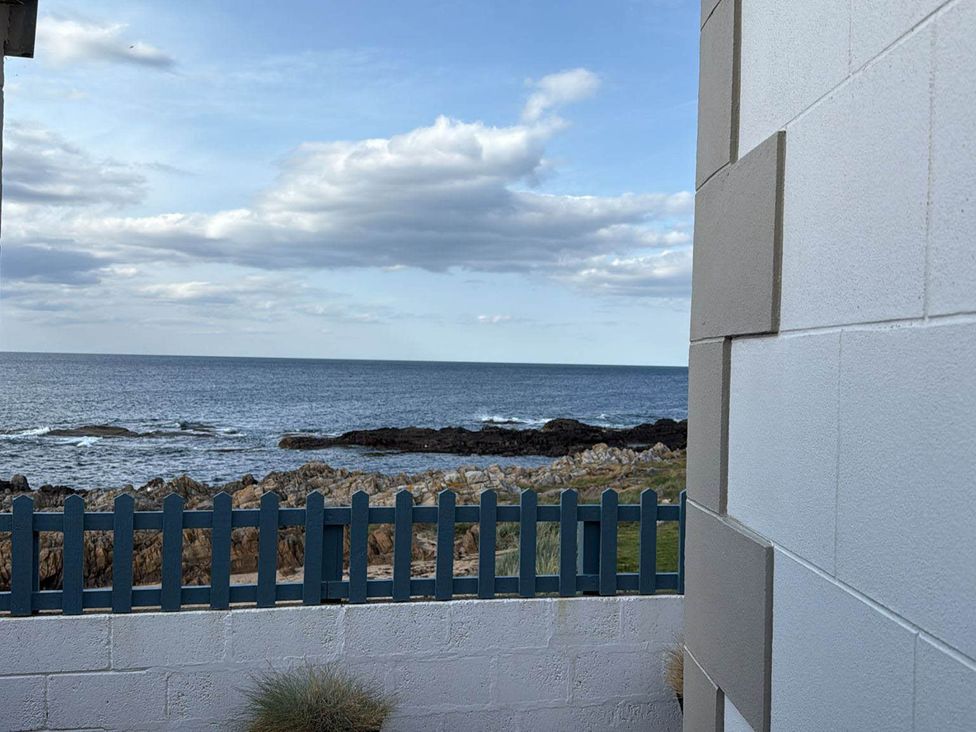 An outdoor area with a view of the ocean and fence at Findochty Beach house Private Garden BeachFront in Findochty