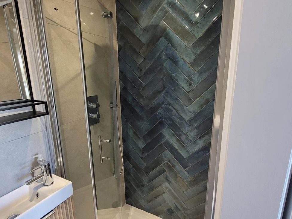 A shower with glass door and a sink in Looe Cottage Seaside views log fire sleeps 4 Looe