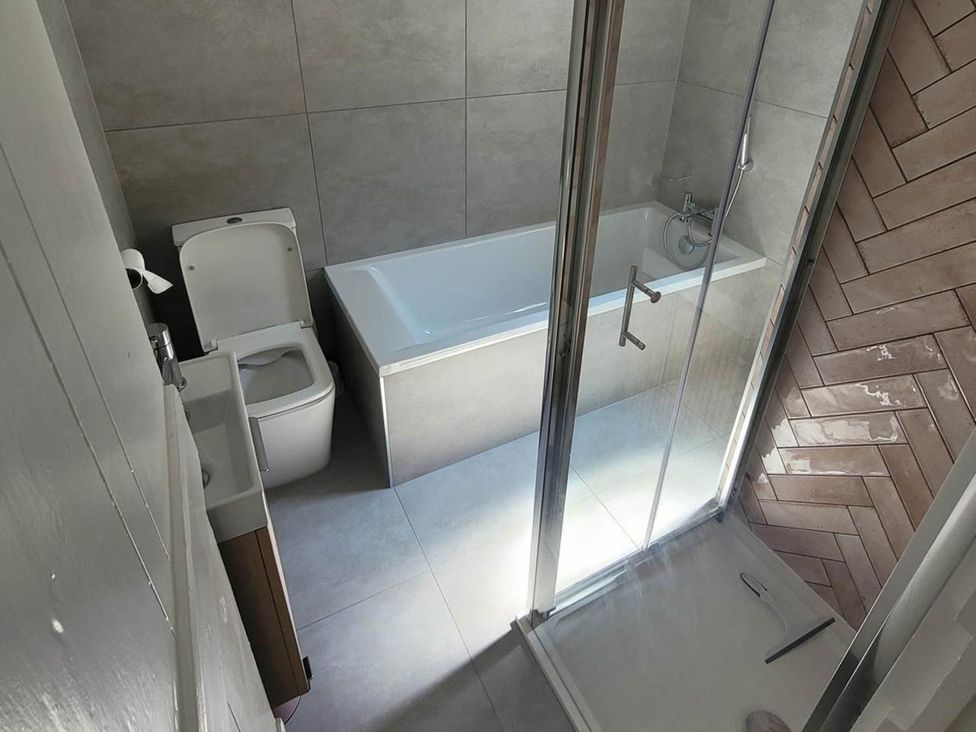A bathroom with a bathtub and shower at Looe Cottage Seaside views log fire sleeps 4 in Looe
