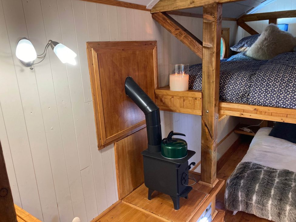 A bedroom with a bunk bed and wood stove at The Owl House in countryside setting near Niwbwrch (newborough)