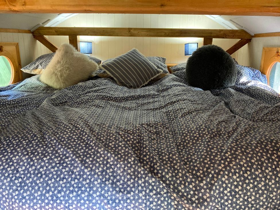 A bed with pillows in a loft at The Owl House in countryside setting near Niwbwrch (newborough)
