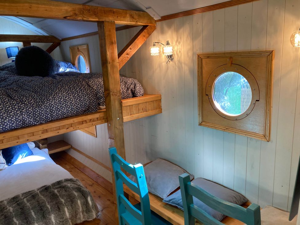 A bedroom with a loft bed and seating area at The Owl House in countryside setting Near Niwbwrch (newborough)