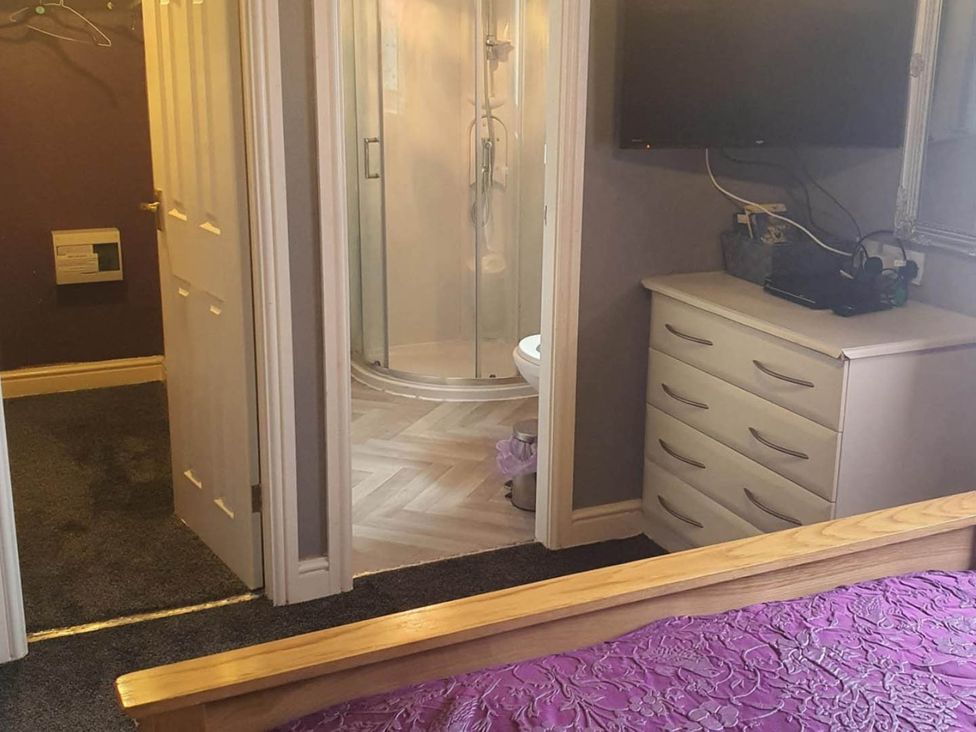 A bedroom with a dresser and a bathroom featuring a shower at Fleetwood