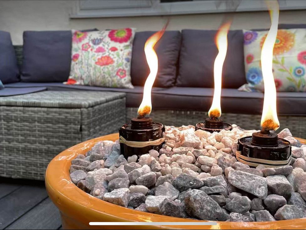 An outdoor seating area with a fire feature and cushions at the property in Tanygrisiau near Blaenau Ffestiniog