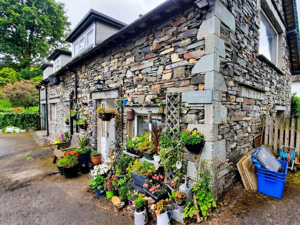 An outdoor area with flower pots and a stone cottage at Fairfield Cottage in Hawkshead