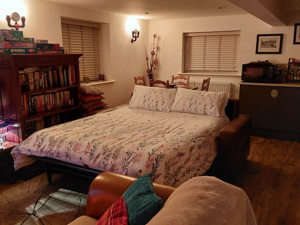 A studio room with a bed and bookshelf at The Old Barn in Hawkshead