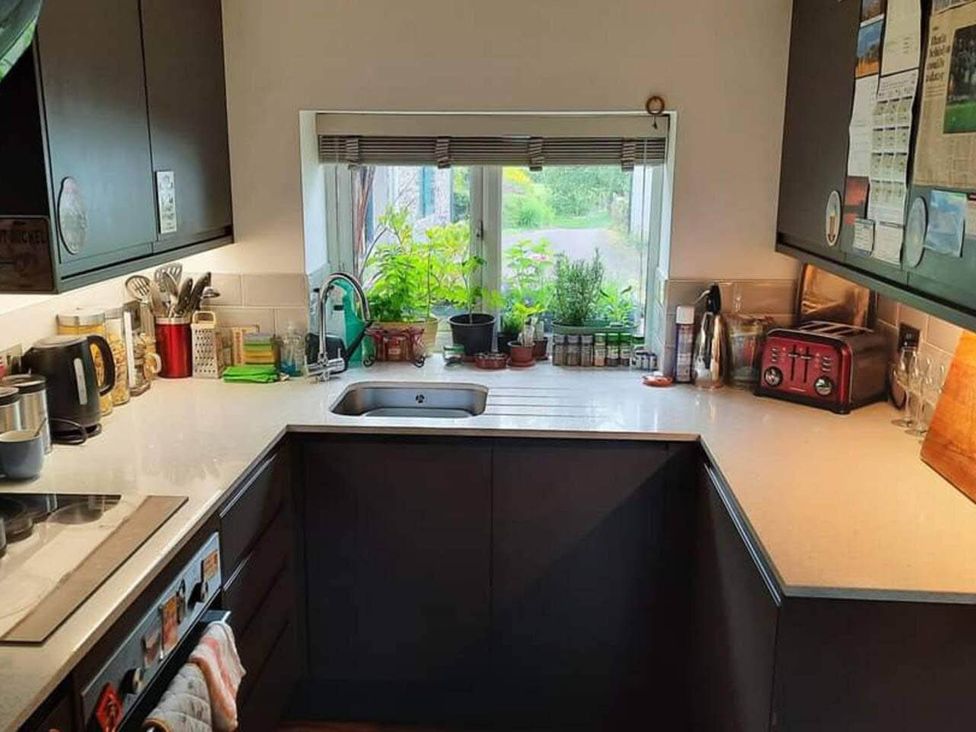A kitchen with a sink and window with plants at The Old Barn in Hawkshead