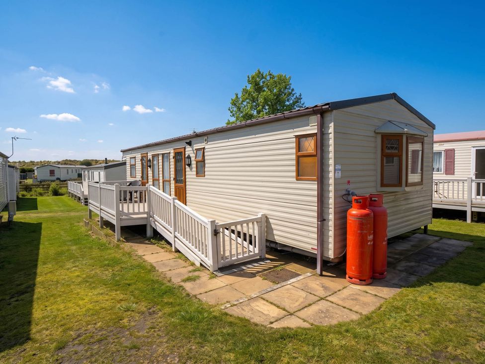 A caravan with steps and gas canisters outside at a campsite