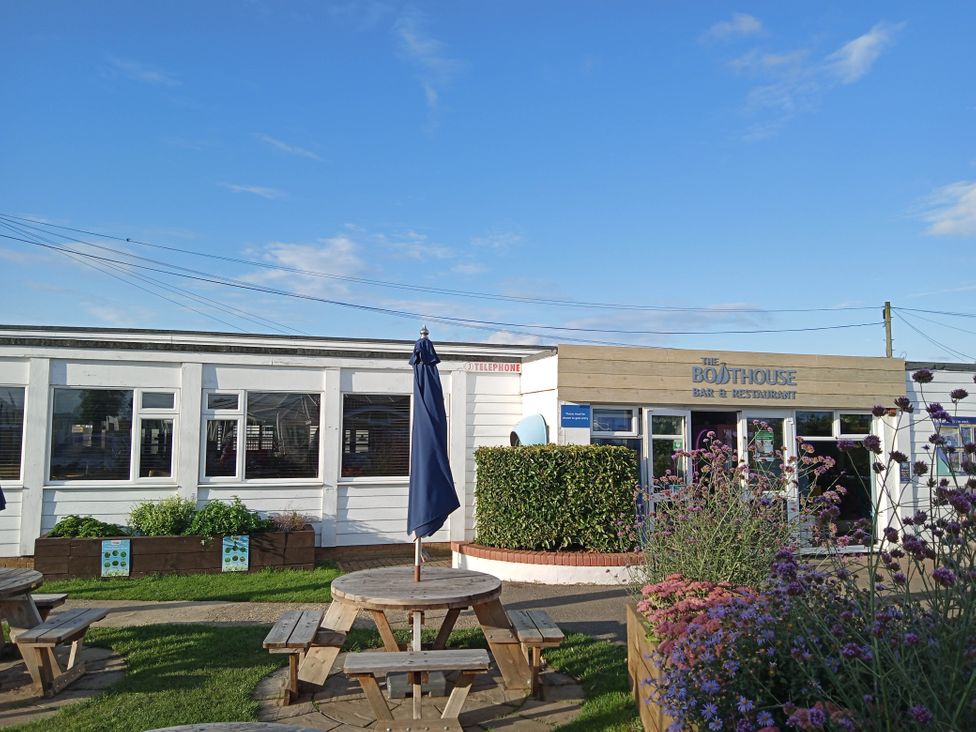An outdoor area with tables and a restaurant called The Boathouse