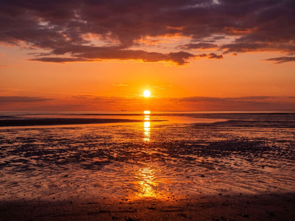 A sunset over the ocean with a ship in the distance at an unknown location