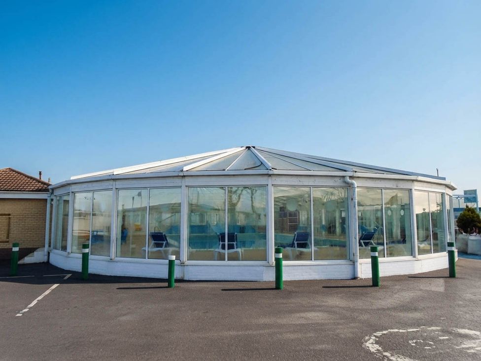 A glass structure with seating in an outdoor area at a property