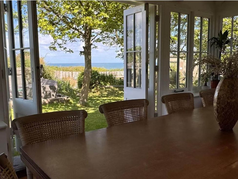 A dining room with a view of the garden and ocean at Norfolk Seaview Luxury Retreat with 7 Bedrooms in Mundesley
