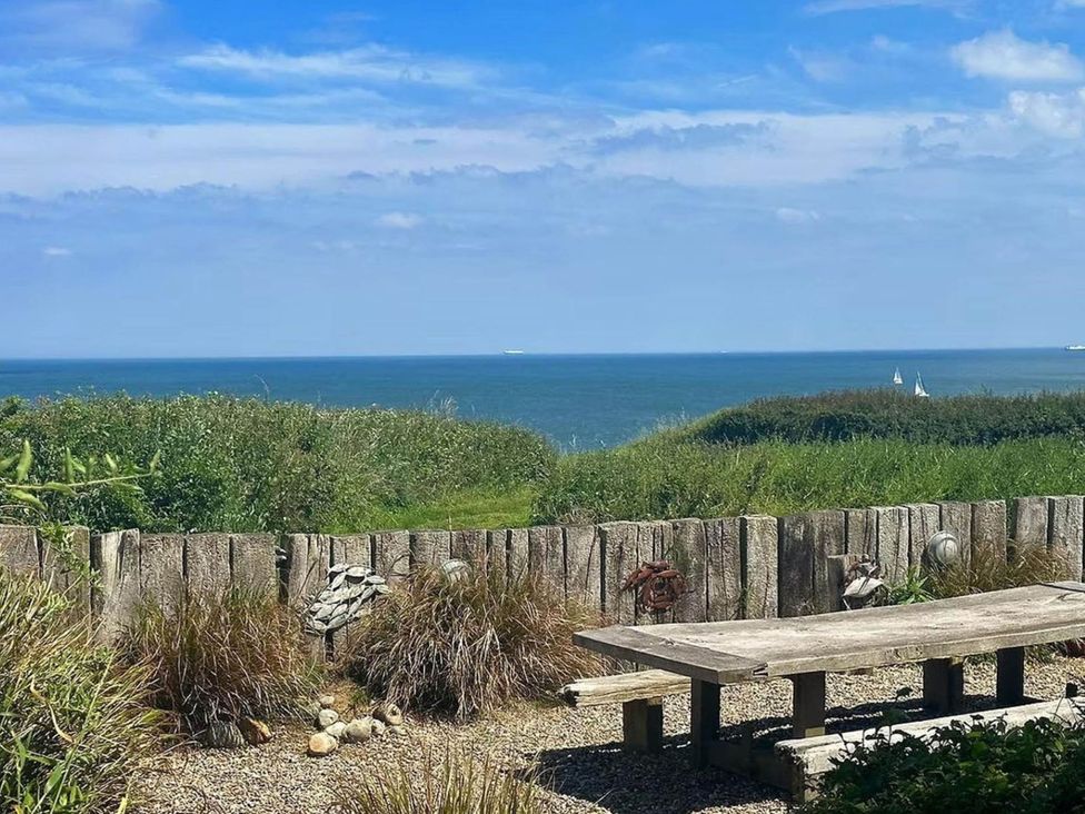 A view of the ocean with a wooden bench at Norfolk Seaview Luxury Retreat with 7 Bedrooms in Mundesley