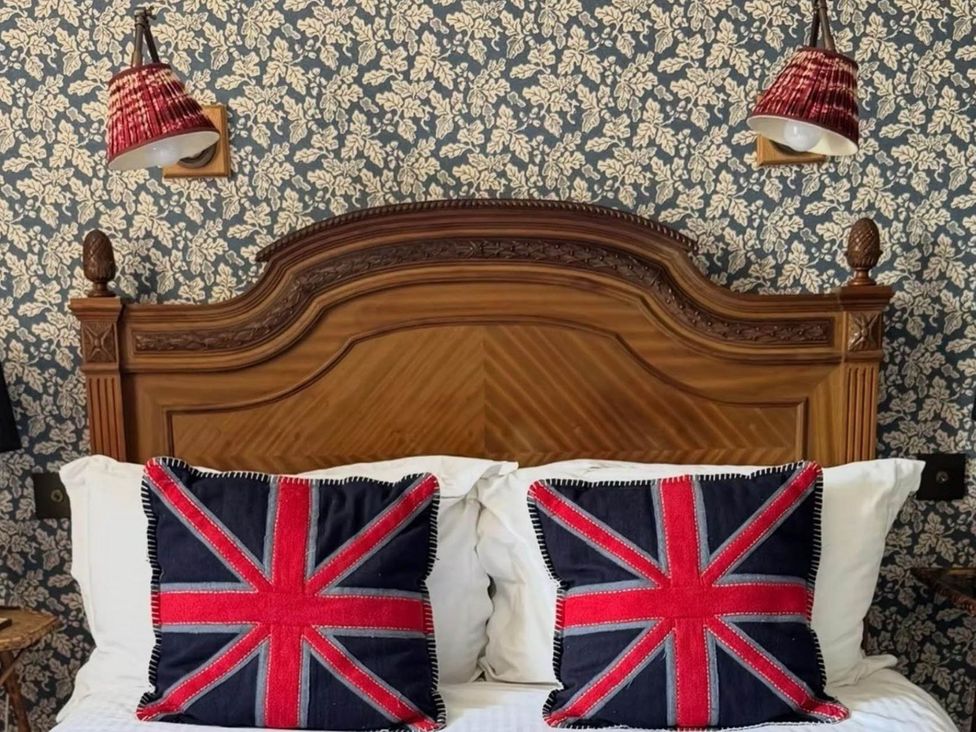 A bedroom with a bed and Union Jack pillows at Norfolk Seaview Luxury Retreat with 7 Bedrooms in Mundesley
