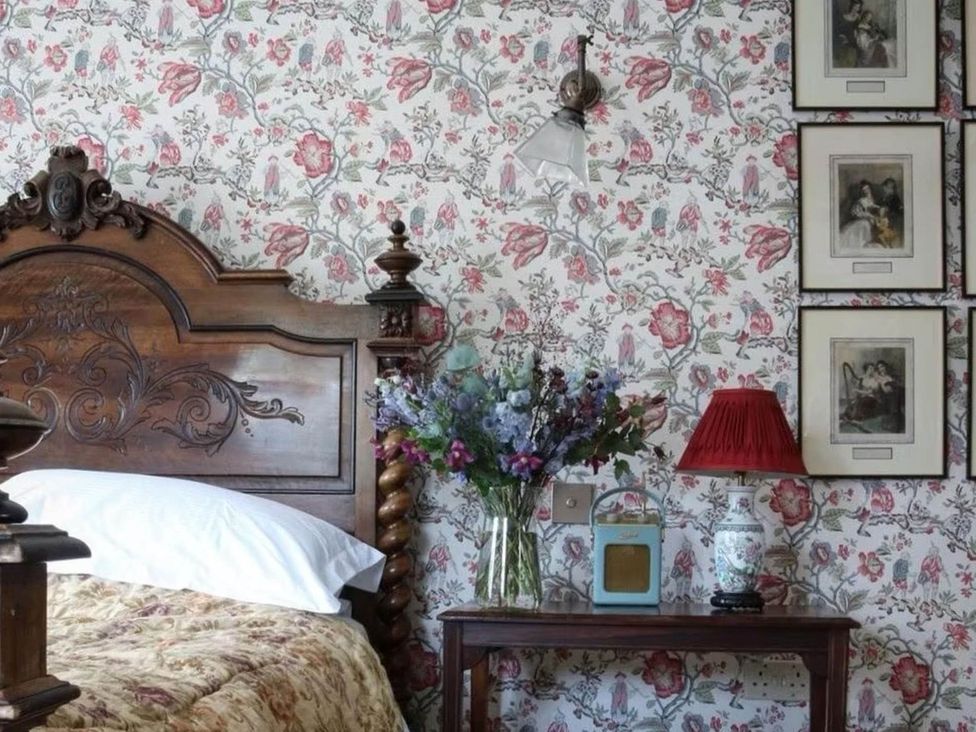 A bedroom with a bed and a table featuring a vase at Norfolk Seaview Luxury Retreat with 7 Bedrooms Mundesley