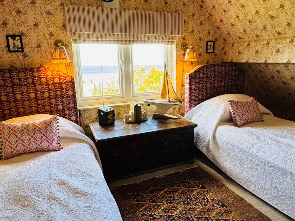 A bedroom with two beds and a wooden table at Norfolk Seaview Luxury Retreat with 7 Bedrooms in Mundesley
