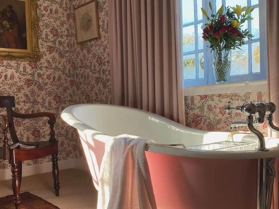 A bathroom with a bathtub and a window at Norfolk Seaview Luxury Retreat with 7 Bedrooms, Mundesley