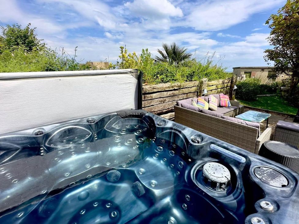 A hot tub next to a seating area with cushions at Norfolk Seaview Luxury Retreat with 7 Bedrooms Mundesley