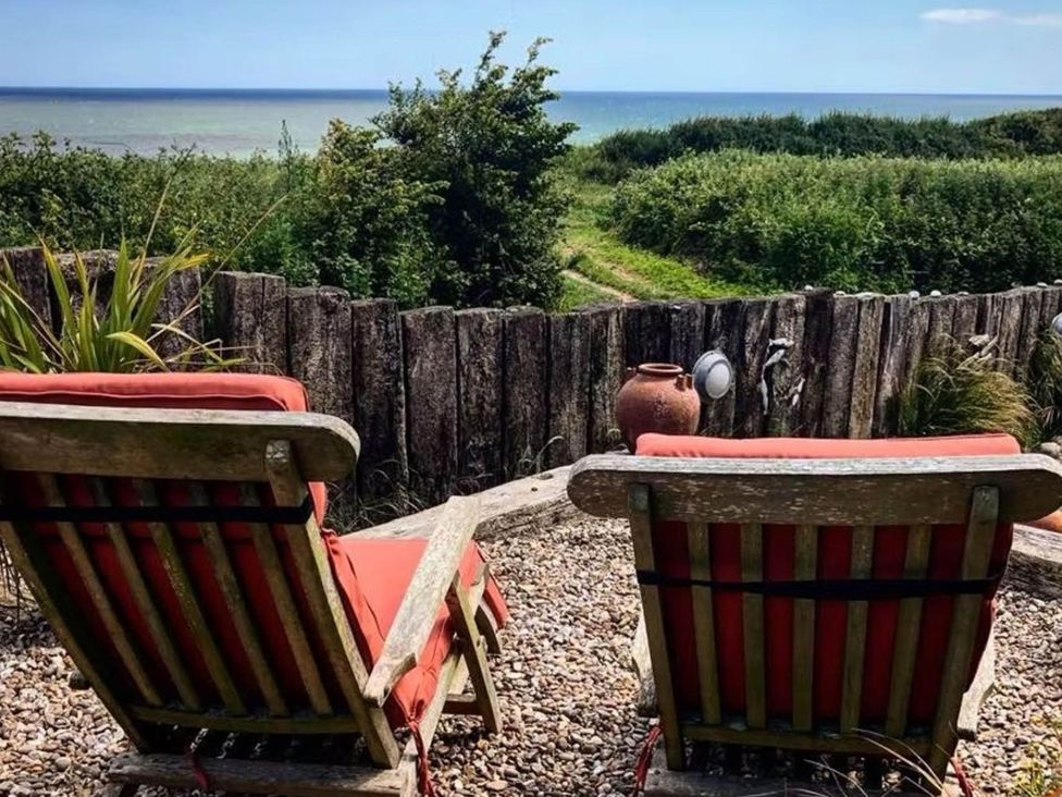 A garden with deck chairs facing the sea at Norfolk Seaview Luxury Retreat with 7 Bedrooms in Mundesley