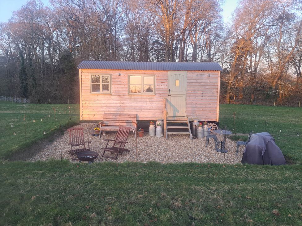 An outdoor area with a tiny house, seating, and a fire pit near Bishop's Waltham
