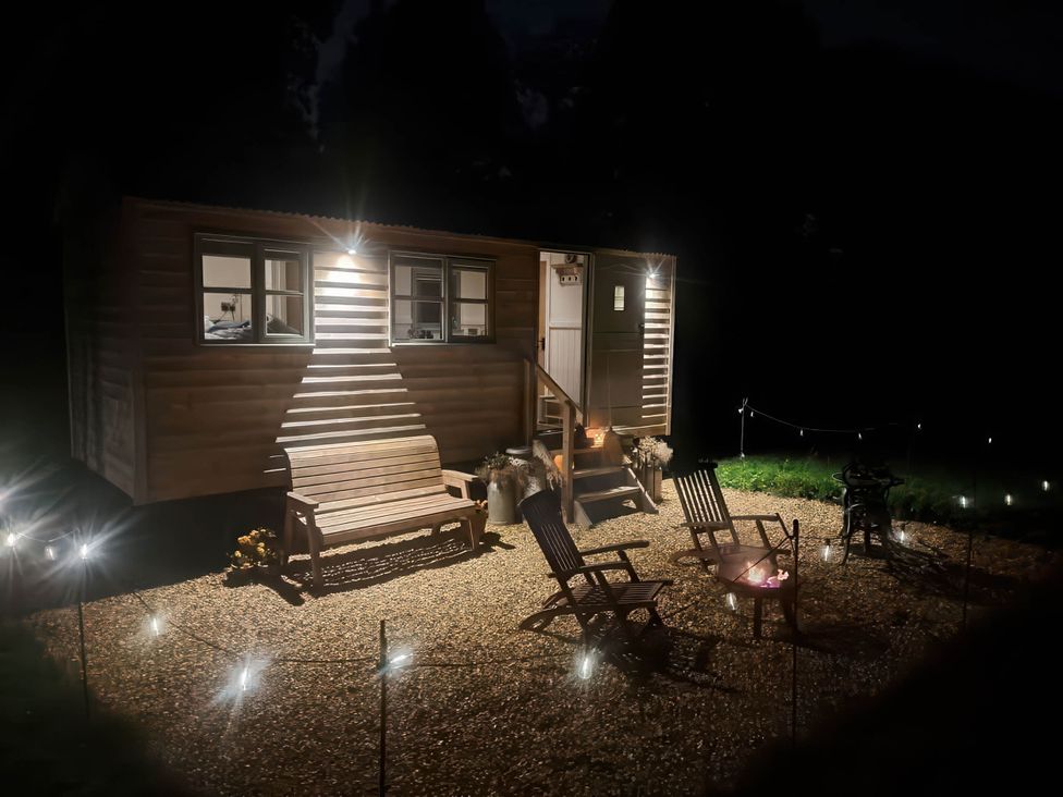 An outdoor area with a cabin, chairs, a bench, and a fire pit at 