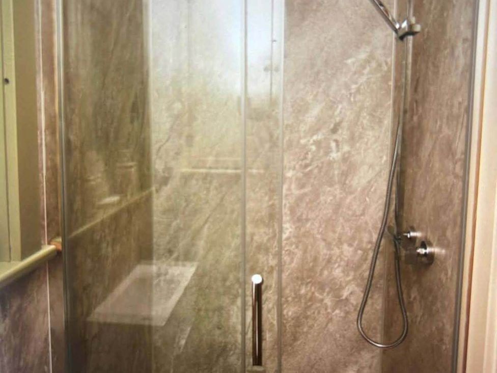 A shower with glass door and wall at 