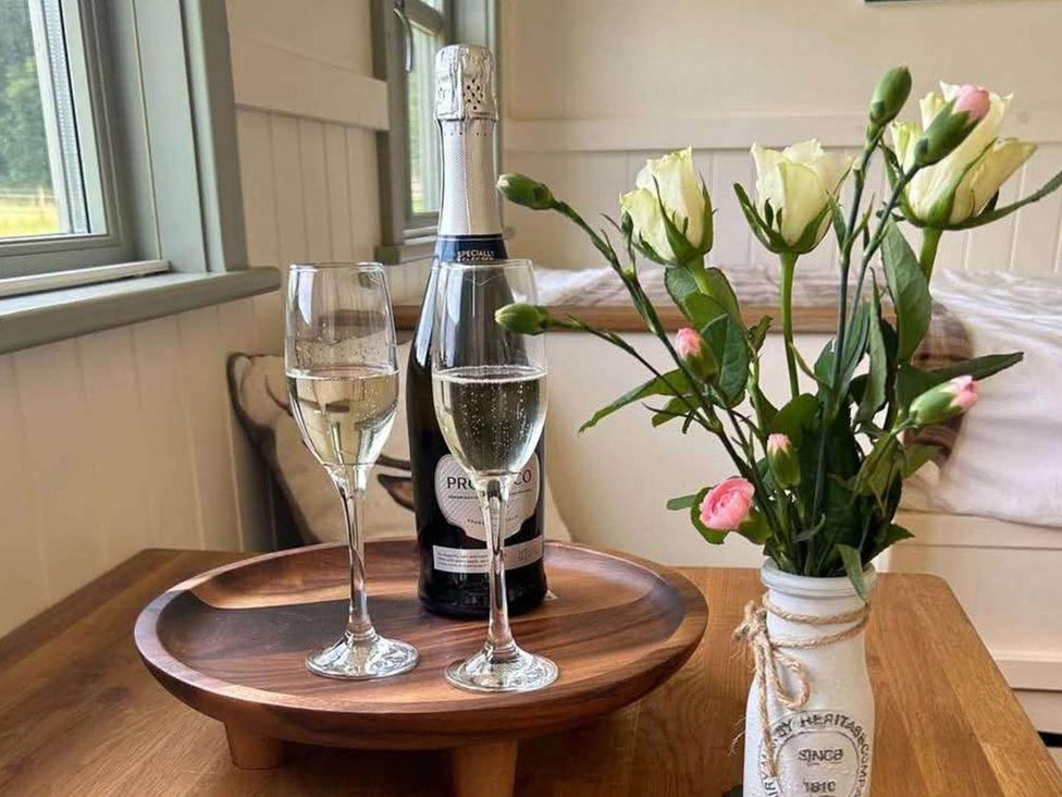 A bottle with champagne glasses and flowers on a tray at 