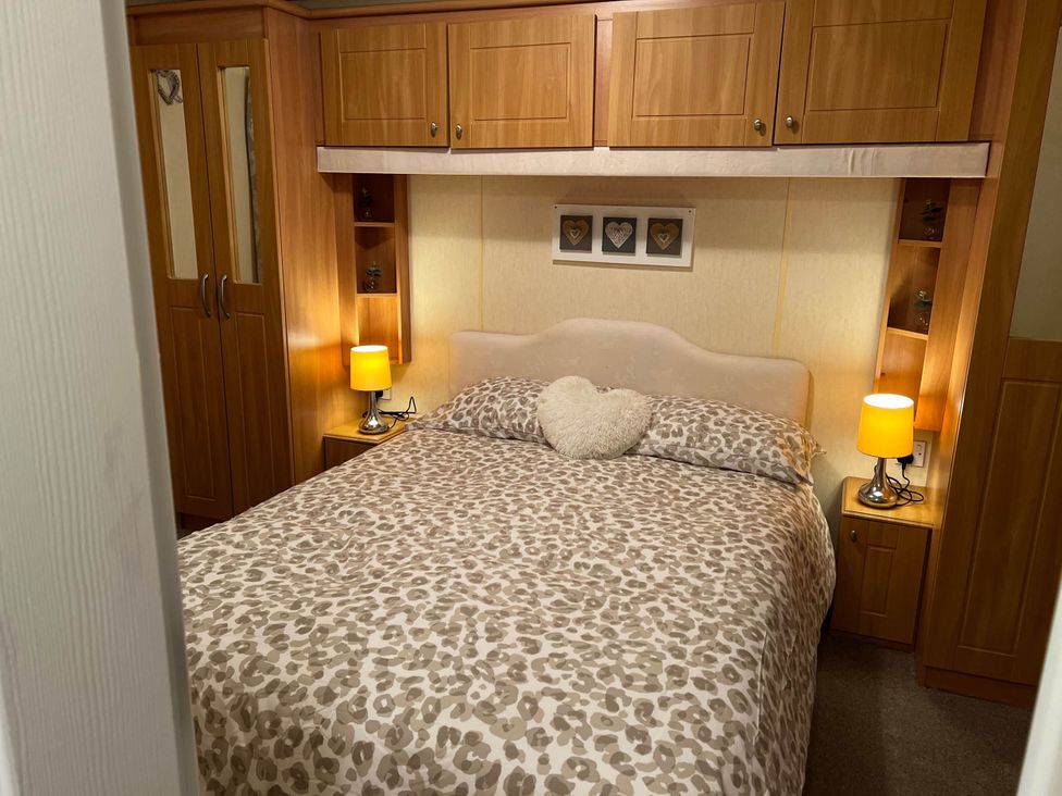 A bedroom with a bed and lamps at a property near West Mersea