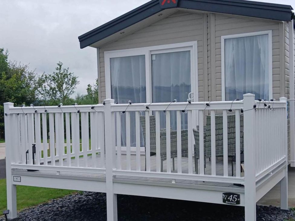 A cabin with a deck and furniture at the property near Flookburgh