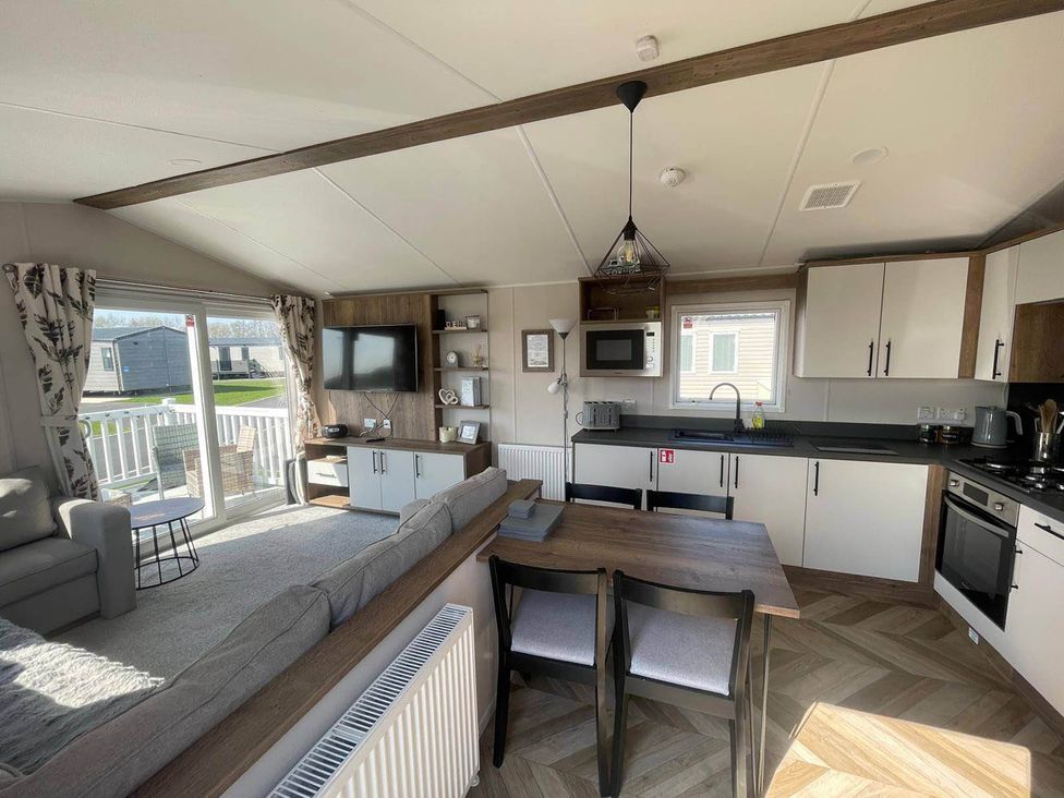 A living room with a sofa and dining area at a holiday home near Flookburgh