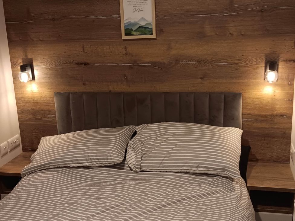 A bedroom with a bed and bedside lamps at The Old Barn Near Flookburgh