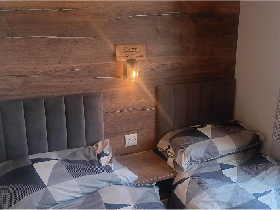 A bedroom with two beds and a wall-mounted light fixture at The Old Barn near Flookburgh