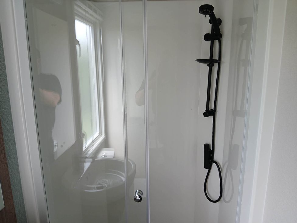 A shower with a glass door and a sink in a bathroom near Flookburgh