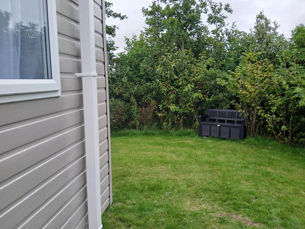 A garden with a seat beside bushes at a property near Flookburgh