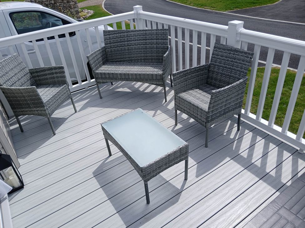 An outdoor patio with gray chairs and a table at The Old Barn in Near Flookburgh